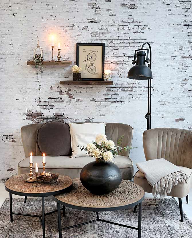 Ipari stílusú, antikolt fekete színű, fém állólámpa enteriőrben bútorokkal, fehér kopott téglafal előtt.