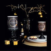 Fekete színű, arany gyűrűvel és csillagokkal díszített karácsonyi gyertyák ünnepi asztalon.