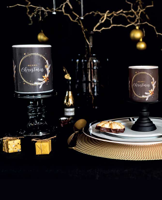 Fekete színű, arany gyűrűvel és csillagokkal díszített karácsonyi gyertyák ünnepi asztalon.