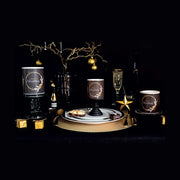 Fekete színű, arany gyűrűvel és csillagokkal díszített karácsonyi gyertyák ünnepi asztalon.