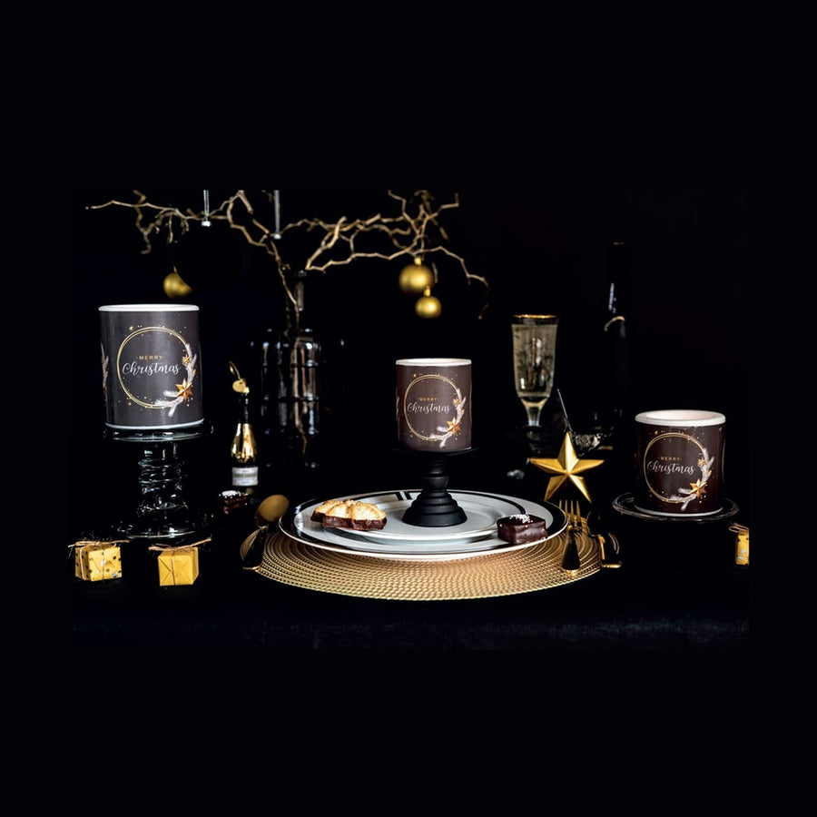 Fekete színű, arany gyűrűvel és csillagokkal díszített karácsonyi gyertyák ünnepi asztalon.