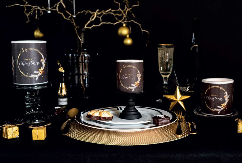 Fekete színű, arany gyűrűvel és csillagokkal díszített karácsonyi gyertyák ünnepi asztalon.