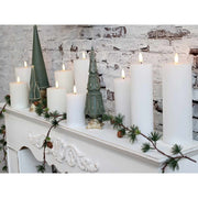 Mű ciprus girland, fehér kandallópárkányon, zöld dekor fenyőfákkal és fehér gyertyákkal.