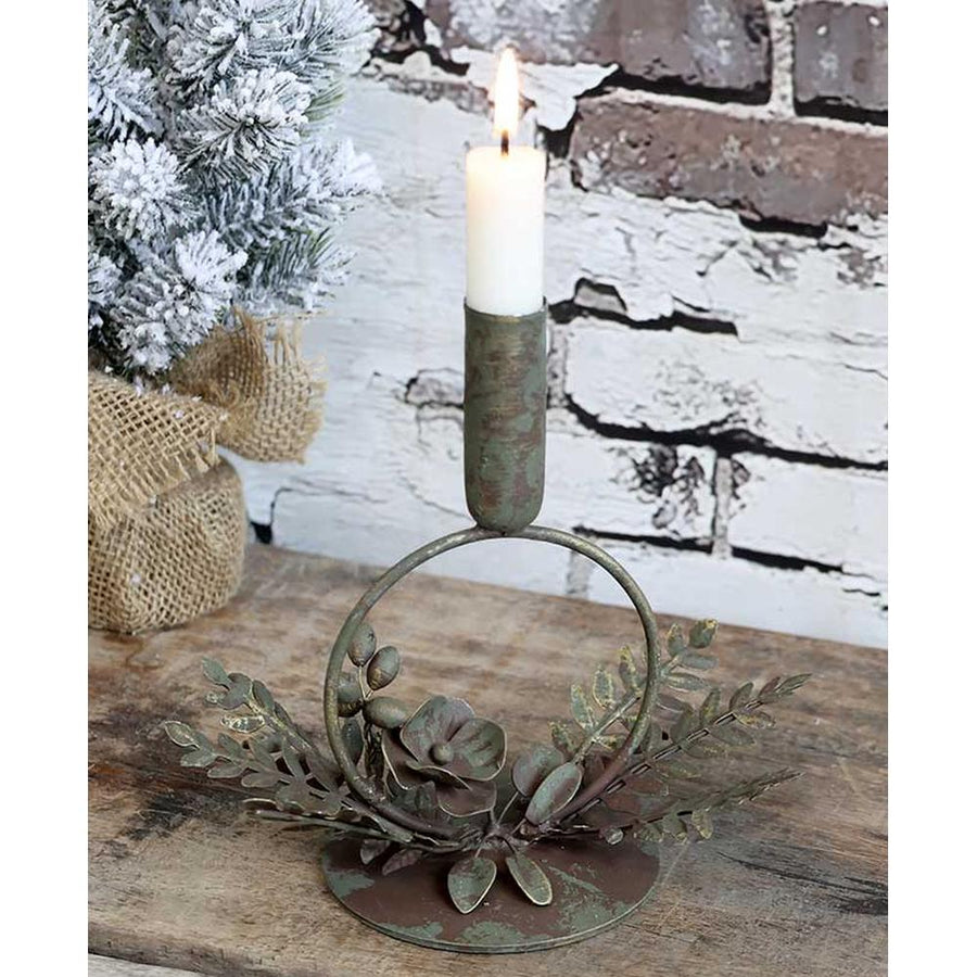 Vintage stílusú, antikolt felületű, fém virágokkal és levelekkel díszített antik réz színű karácsonyi gyertyatartó fa asztalon romos téglafal előtt 