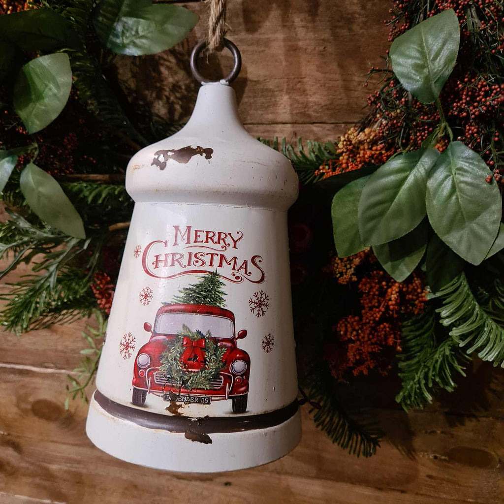 Vidéki, farmhouse stílusú,, antikolt, kopott fehér színű, Merry Christmas feliratú, karácsonyi koszorús, piros színű platós farm kocsival díszített, fémből készült karácsonyi harang.