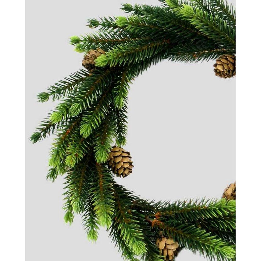 Apró fenyőtobozokkal díszített, élethű megjelenésű, mesterséges mű fenyőágakból készült ünnepi gyertyagyűrű koszorú.