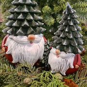 Karácsonyi manók fenyősapkában, zöld fenyők között.