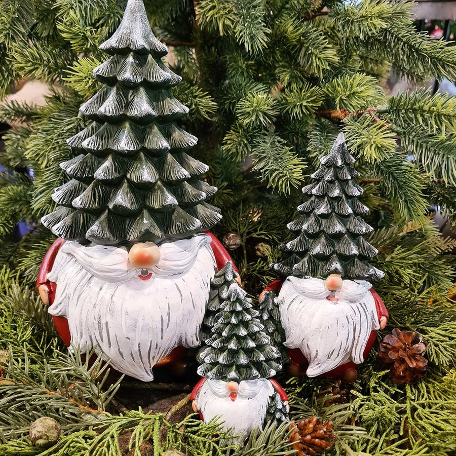 Karácsonyi manók fenyősapkában, zöld fenyők között.