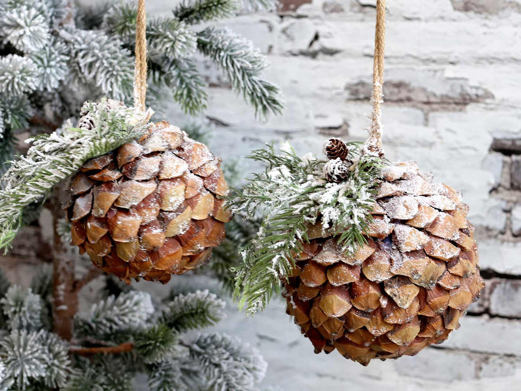 Kétféle méretű, vidéki stílusú,, fenyőággal díszített, havas felületű, karácsonyi toboz gömb dísz.