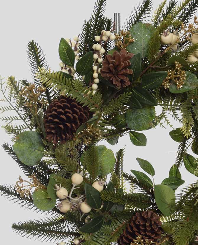 Karácsonyi koszorú, fenyőágakból és eukaliptuszokból, fenyőtobozokkal és fehér erdei bogyókkal díszítve.