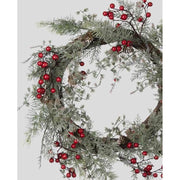 Piros bogyókkal díszített, ezüstös zöld színű mesterséges fenyőágakból készült karácsonyi koszorú, ajtódísz.
