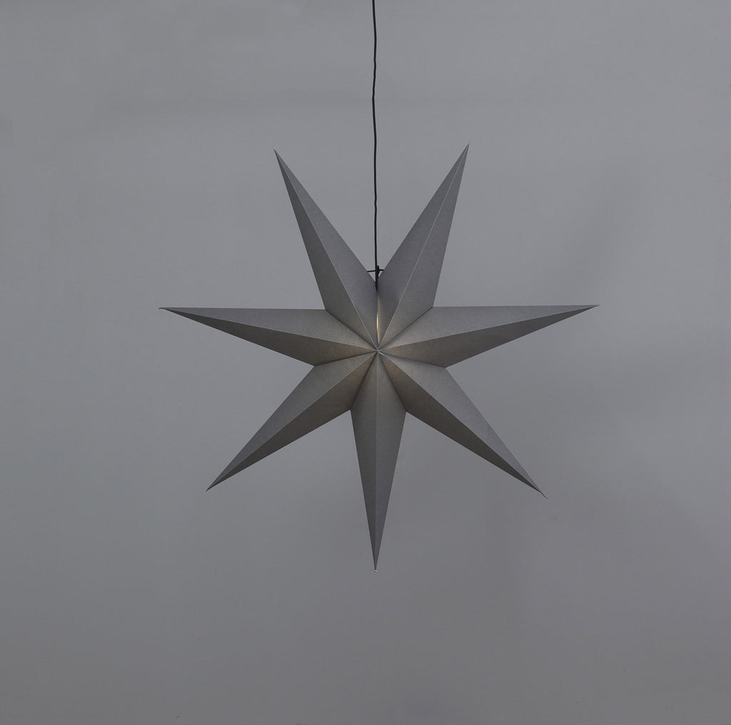 Szürkeszínű, karácsonyi papírcsillag lámpa szürke háttér előtt.