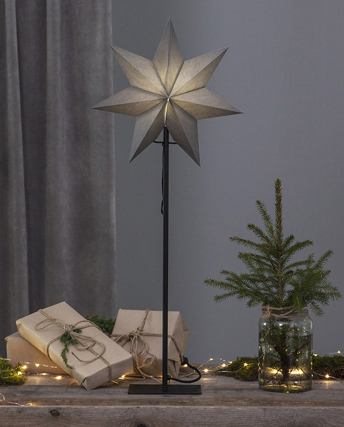 Szürke színű világító karácsonyi papírcsillag, ajándékokkal és fenyőággal. 