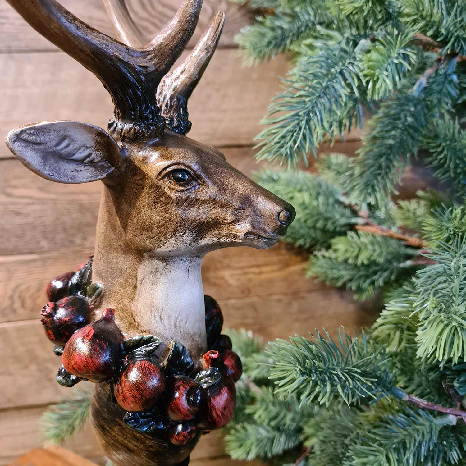 Vintage stílus, csipkebogyó koszorúval díszített, dekoratív karácsonyi szarvas mellszobor, fenyőfával.