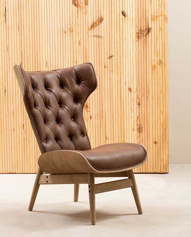 Prémium minőségű, kortárs stílusú, hajlított szilfából készült bőrhatású barna színű bársonnyal kárpitozott szárnyas relaxációs szék natúr színű fa lambéria előtt 