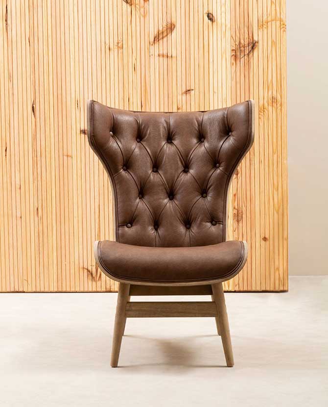 Prémium minőségű, kortárs stílusú, hajlított szilfából készült bőrhatású barna színű bársonnyal kárpitozott szárnyas relaxációs szék szembenézeti képe fa lambéria előtt 