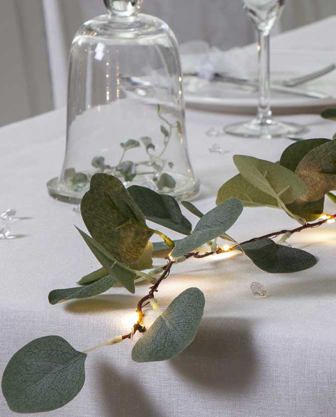 Led-es eukaliptusz girland közeli képe , ünnepi fehér asztalon 