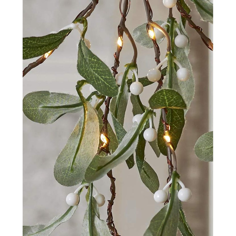 Karácsonyi led-es fagyöngy ág műnövény közeli képe a növény leveleiről, fehér bogyós terméséről, és led fényforrásokról