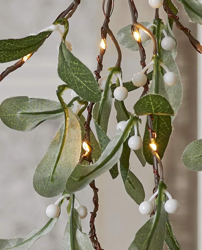Karácsonyi led-es fagyöngy ág műnövény közeli képe a növény leveleiről, fehér bogyós terméséről, és led fényforrásokról