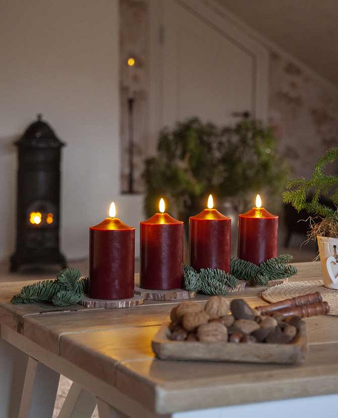 Bordó színű karácsonyi led gyertyák fa a asztalon, fenyőágakkal 