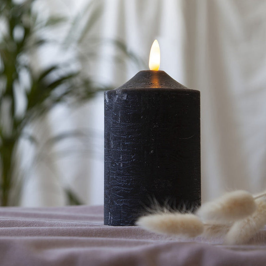 Fekete színű LED gyertya asztalon, száraz virágokkal.