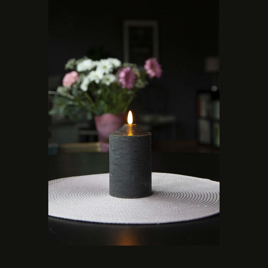 Fekete színű LED gyertya asztalon, virágcsokorral. 