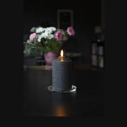 Fekete színű LED gyertya asztalon, virágcsokorral.