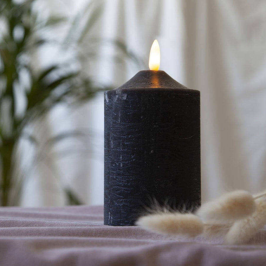 Fekete színű LED gyertya asztalon, száraz virágokkal.
