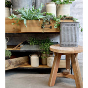 Natúr színű, loft stílusú 2 fiókos, 2 polcos konzolasztal, zöld növényekkel és kaspókkal.