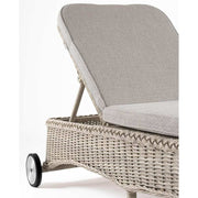 Vidéki vintage stílusú, kerekekkel felszerelt,, dönthető háttámlájú, natúr színű műrattan napozóágy, bézs színű olefin fekvőpárnával,