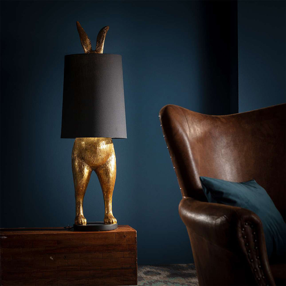 Aranyszínű, rejtőzködő nyuszi figurás, díjnyertes dizájn állólámpa, feketeszínű lámpaernyővel, bőr fotellel.
