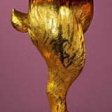 Aranyszínű, rejtőzködő nyuszi figurás, 74 cm magas, kortárs, glamour stílusú, díjnyertes dizájn asztali lámpa, türkizszínű lámpaernyővel, mályva színű fal előtt.