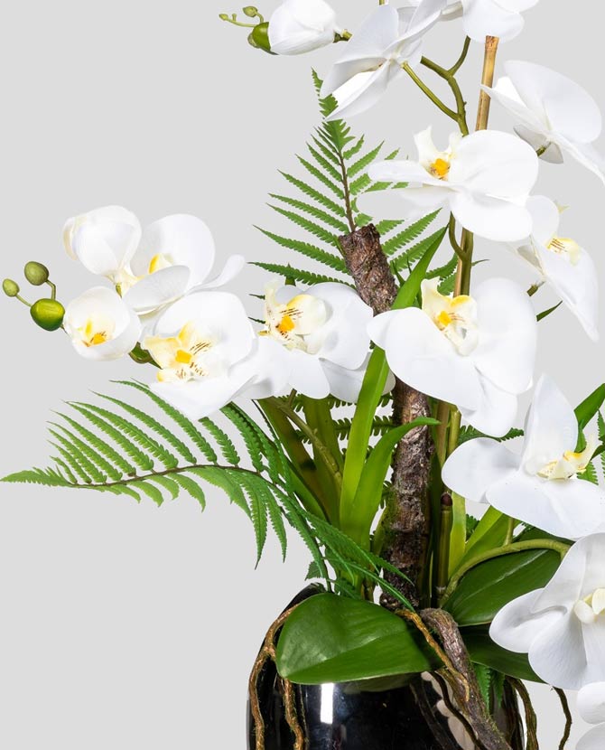 Fehér színű mű orchidea kompozíció, ezüst színű fém vázában.
