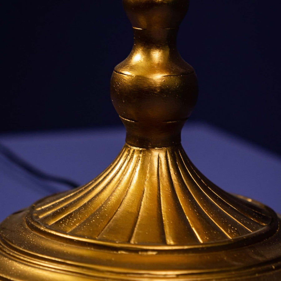 Díszes, aranyszínű fém talapzat.