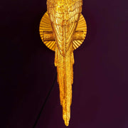 Arany színű papagáj hosszú farka, lila színű háttér előtt. 