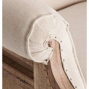 Prémium kategóriás, gyarmati stílusú, újrahasznosított trópusi fából készült, ekrü színű szövettel kárpitozott fotel karfájának közeli képe