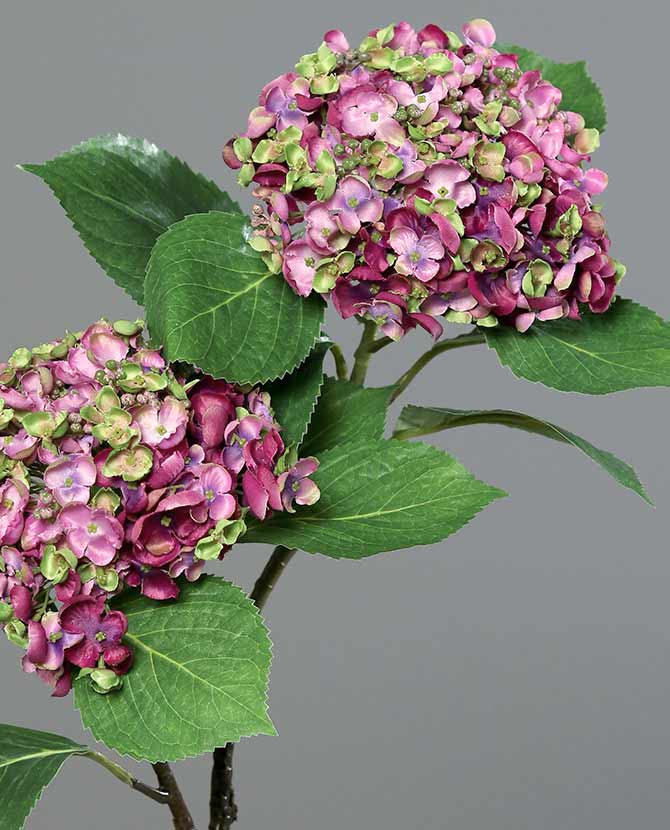 Lilás-zöld színárnyalatú virágfejjel díszített mesterséges mű hortenzia ág.