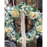 Élethű mesterséges művirágokból készült, ekrü színű csipkeszalagokkal díszített ajtókopogtató koszorú