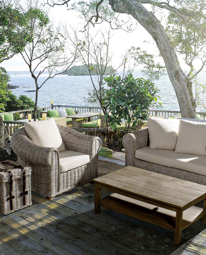 Tengerparti teraszon álló mediterrán stílusú rattan fotel és kanapé.