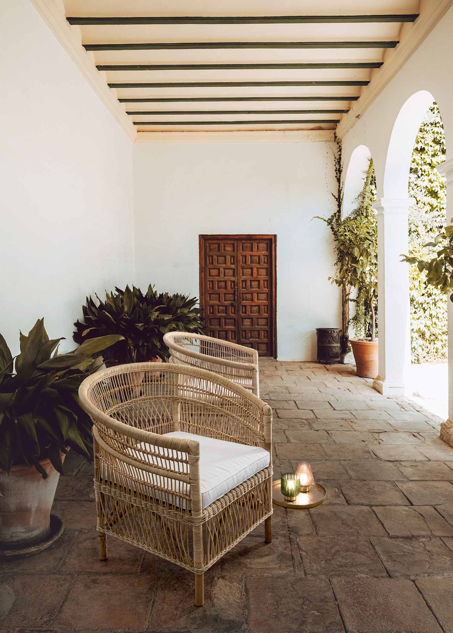 Mediterrán stílusú, fedett teraszon álló rattan fotelek.