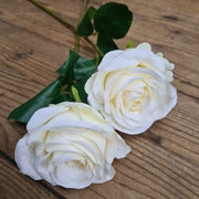 Kém színű műrózsák natúr színű fa asztalon.