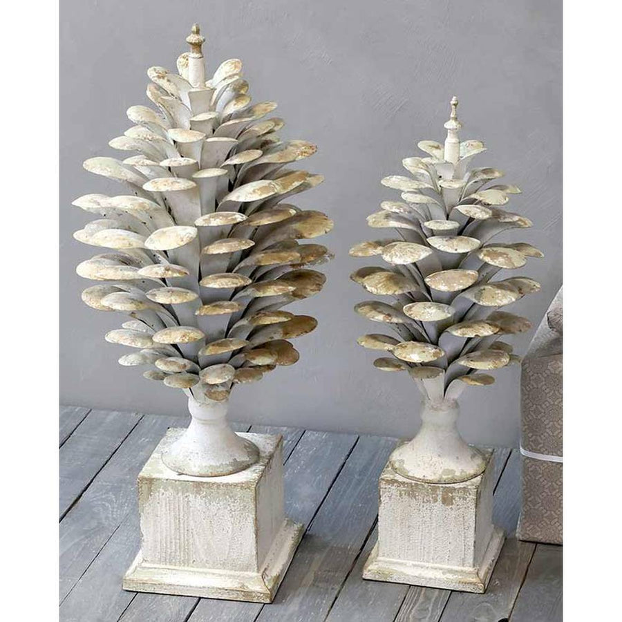 Kétféle méretű, antikolt krémszínű, fém toboz dísz szürke fal előtt.