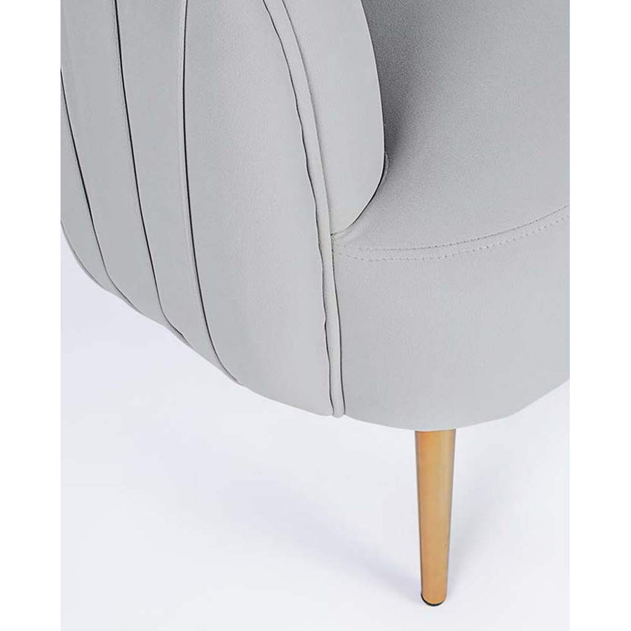 Skandináv stílusú, halványszürke színű bársonnyal kárpitozott fotel, aranyszínű fém lábak részlete.