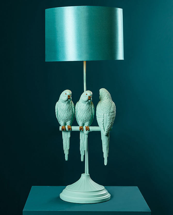 Türkizszínű papagáj figurákkal díszített, 79 cm magas, trópusi, glamour stílusú asztali lámpa kék háttér előtt.