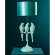 Türkizszínű papagáj figurákkal díszített, 79 cm magas, trópusi, glamour stílusú asztali lámpa kék háttér előtt.