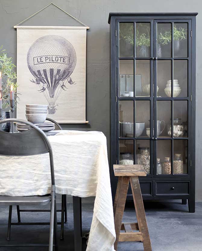 Antik fekete színű, vintage stílus vitrines szekrény, légballonosképpel, terített étkezőasztallal. 