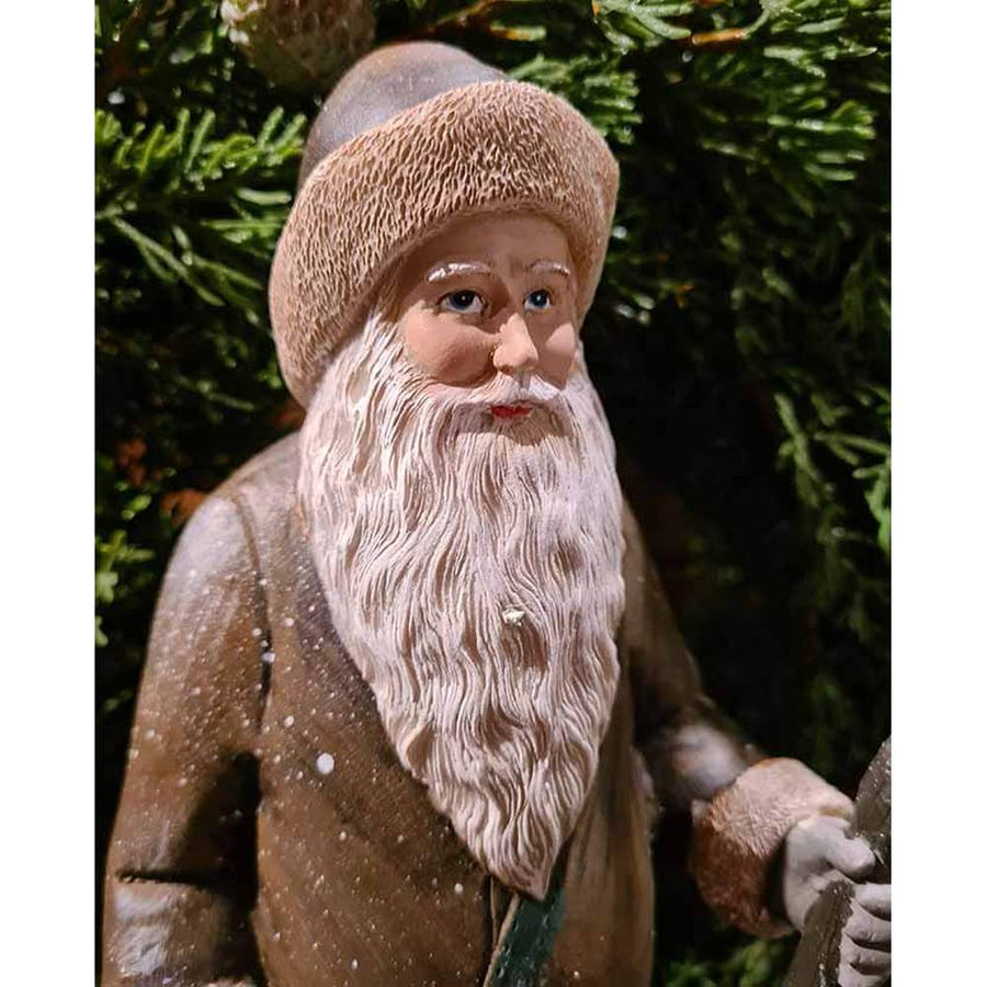 Prémium minőségű, vintage stílusú, 30 cm magas, barna színű, klasszikus Télapó figura zöld fenyőkoszorú előtt