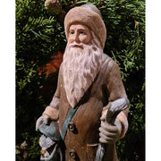 Prémium minőségű, vintage stílusú, 30 cm magas,  barna színű, klasszikus Télapó figura zöld fenyőkoszorú előtt 