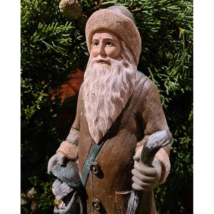 Prémium minőségű, vintage stílusú, 30 cm magas,  barna színű, klasszikus Télapó figura zöld fenyőkoszorú előtt 