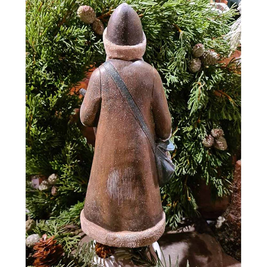 Prémium minőségű, vintage stílusú, 30 cm magas, barna színű, klasszikus Télapó figura zöld fenyőkoszorú előtt